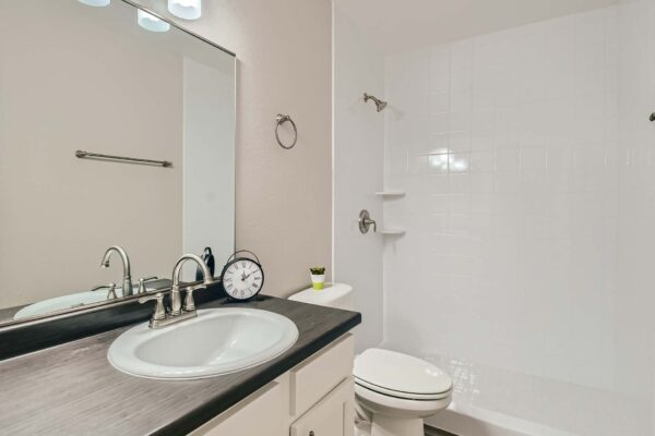 Tempe Vista apartment bathroom with white cabinets, dark counters, and tiled shower.