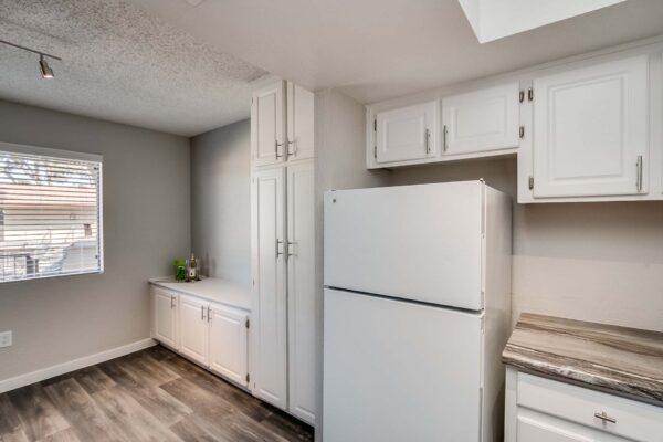Tempe Vista apartment kitchen with wood style floor, white cabinets, dark counters, and white appliances.