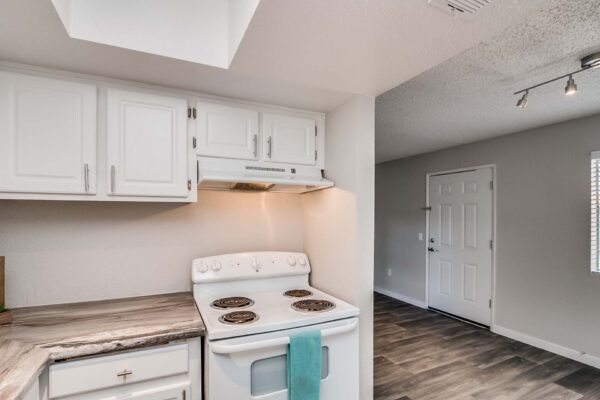 Tempe Vista apartment kitchen with wood style floor, white cabinets, dark counters, and white appliances.