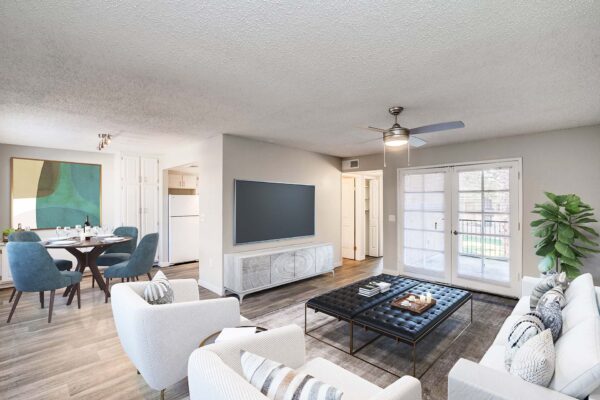 Tempe Vista apartment living room with plush seating, wall mounted TV, and balcony door.