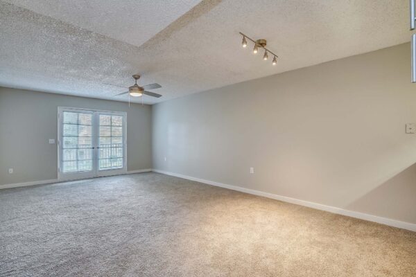 Tempe Vista apartment living room with plush carpet and balcony door.