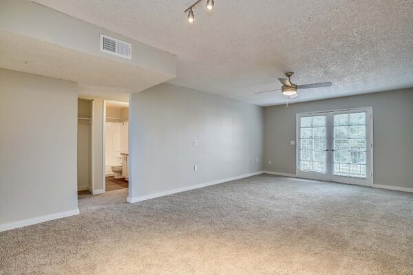 Tempe Vista apartment living room with plush carpet and balcony door.