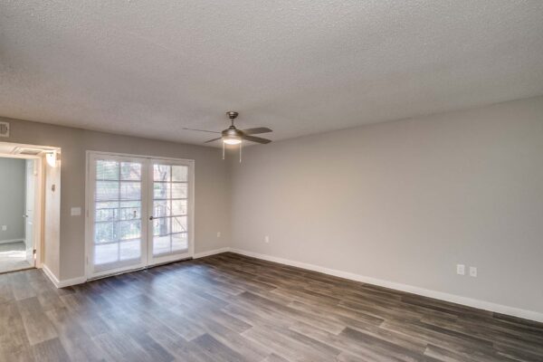 Tempe Vista apartment living area with wood style floor, ceiling fan, and balcony doors.