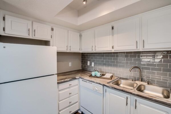 Tempe Vista apartment kitchen with white cabinets, dark counters, tiled backsplash, and white appliances.