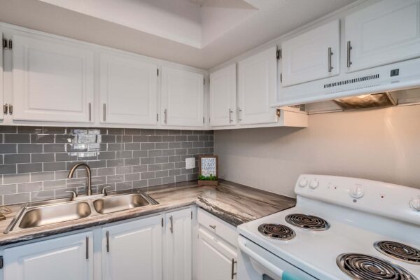 Tempe Vista apartment kitchen with white cabinets, dark counters, tiled backsplash, and white appliances.