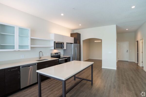 The Locale apartment kitchen with wood style floor, two tone cabinets, and stainless steel appliances.