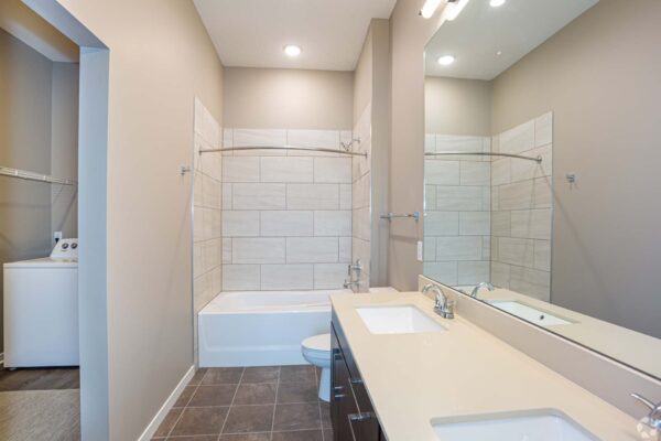The Locale apartment bathroom with tile, dark cabinets, light counters, and tiled shower tub.