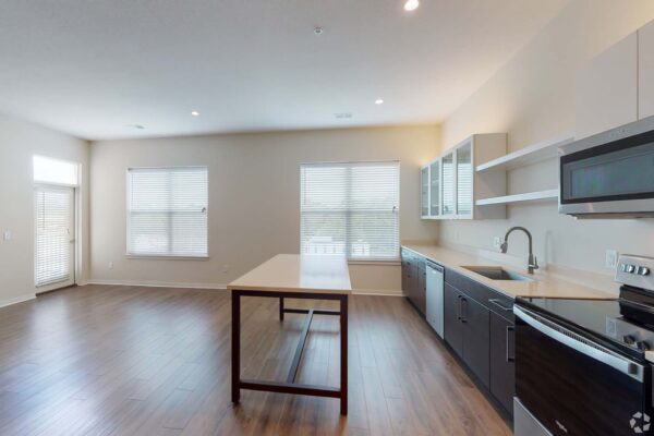 The Locale apartment kitchen with wood style floor, two tone cabinets, and island table.