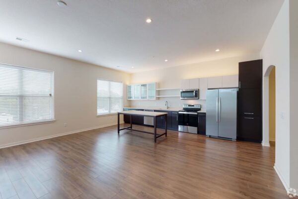 The Locale apartment kitchen with wood style floor, two tone cabinets, stainless steel appliances, and island table.