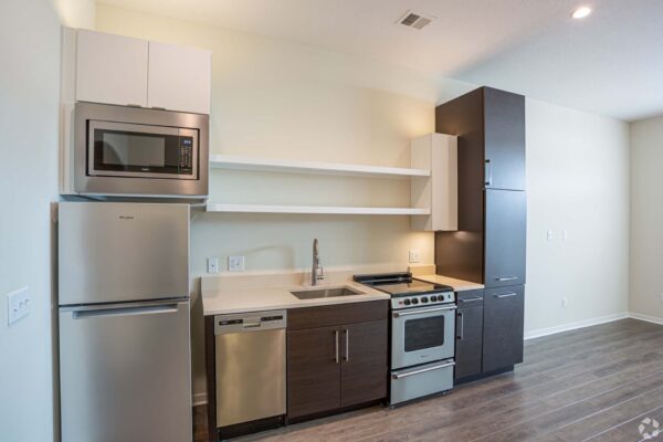 The Locale apartment kitchen with wood style floors, two tone cabinets, and stainless steel appliances.