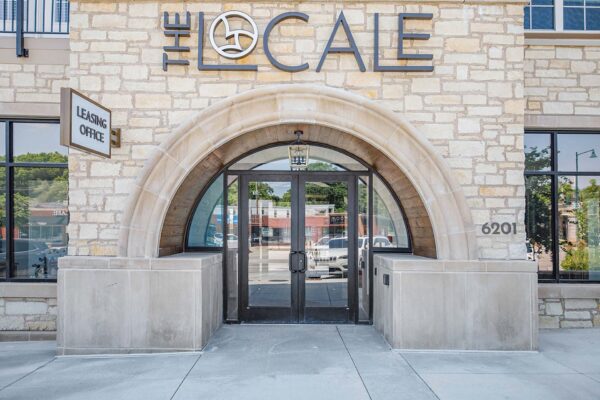 The Locale apartments entrance with large stone archway and sign.