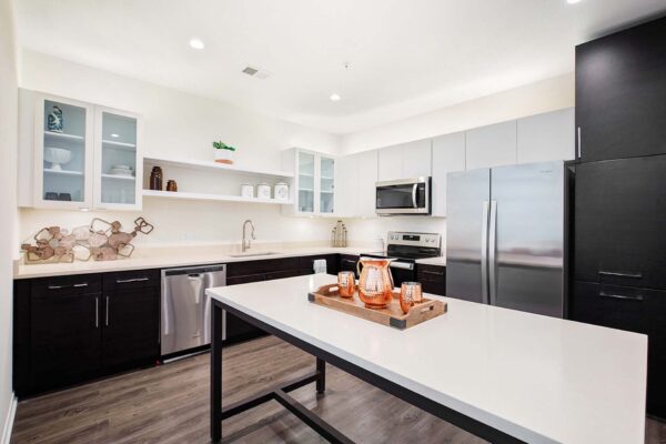 The Locale apartment kitchen with wood style floor, two tone cabinets, and stainless steel appliances.
