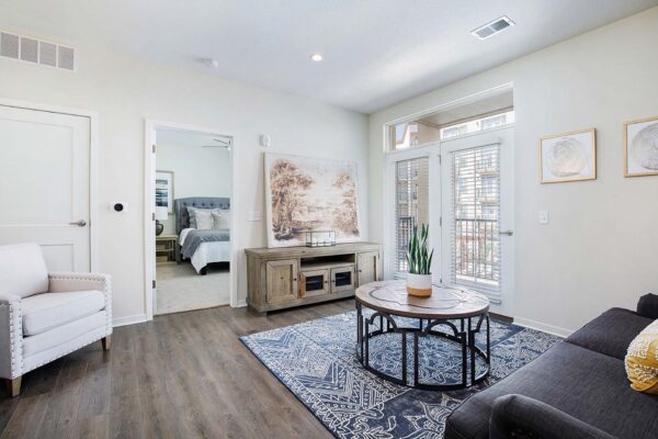 The Locale apartment living room with wood style floor, plush seating, and balcony door.