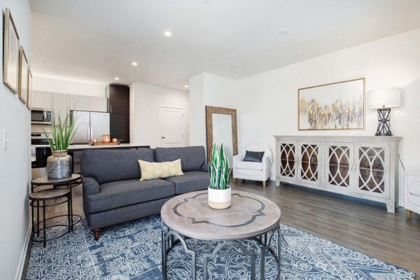 The Locale apartment living room with wood style floor, plush seating, and cabinet with decor.