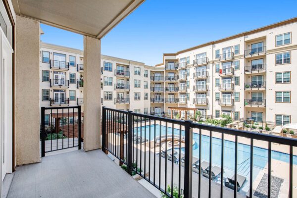 The Locale apartment balcony with metal railing overlooking pool area.