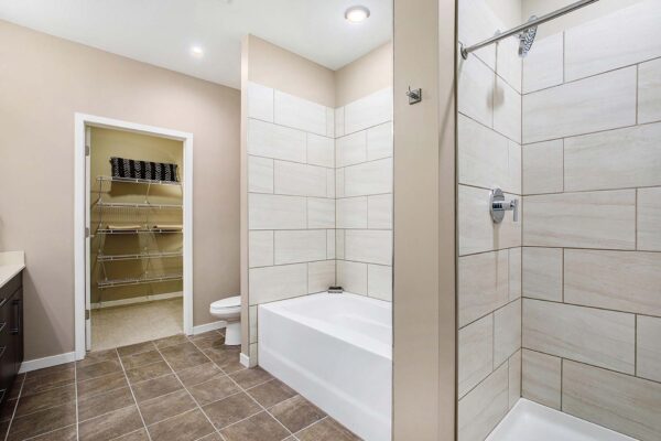 The Locale apartment bathroom with tiled floor and separate shower and tub.