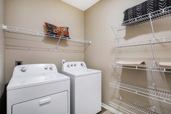 The Locale apartment laundry room with washer, dryer, and built in wire shelves.