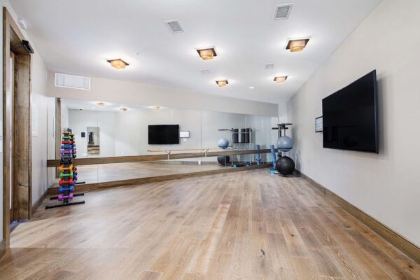 The Locale apartment fitness center with wood style floor, mirror wall, and large TV.