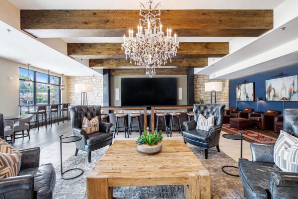 The Locale apartment clubroom with plush leather arm chairs, elegant wood architecture, and large chandelier.