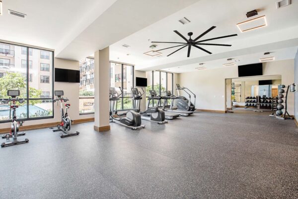 The Locale apartments fitness center with cardio machines, weight equipment, and large windows.