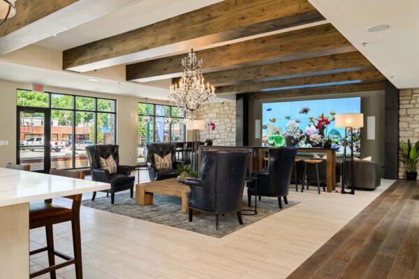 The Locale apartments clubroom with large TV screen, plush seating, and elegant wood decor.