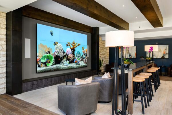 The Locale apartments clubroom with plush seating, large TV screen, and elegant wood architecture.