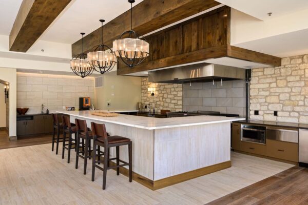 The Locale apartments community kitchen with large bar, stools, and restaurant style appliances.