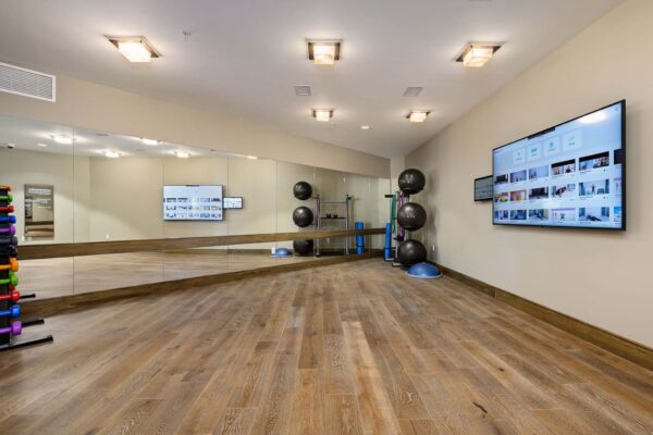 The Locale apartments fitness center with wood style floor, mirror wall, and large TV.