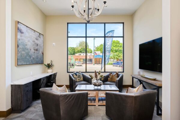 The Locale apartments lobby with plush seating, wall mounted TV, desk, and large windows.