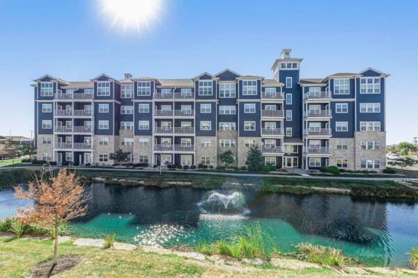Village West apartments pond with fountain and grassy lawns.