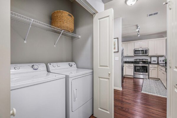 Village West apartment laundry closet with washer, dryer, and built in wire shelf.