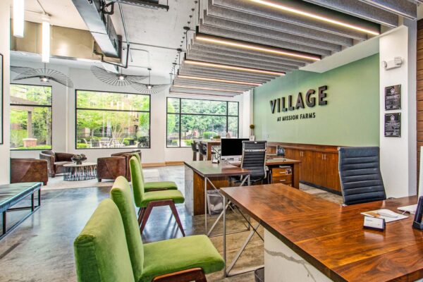 Village at Mission Farms apartments lobby with polished concrete floors, wood desks, and comfortable chairs.