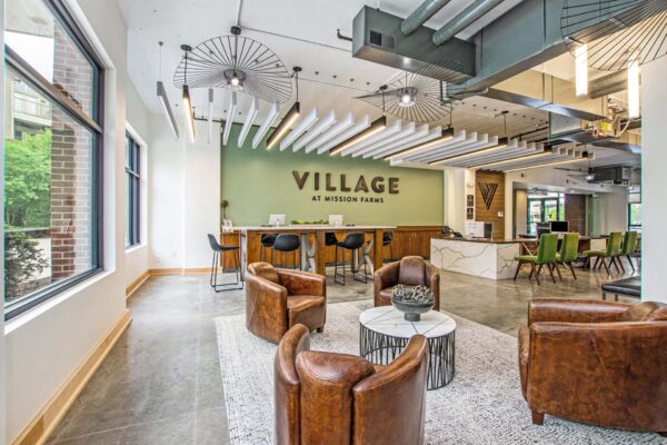Village at Mission Farms apartments lobby with leather chairs, concrete floors, modern lights, and large windows.