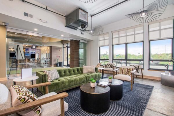 Village at Mission Farms apartments lobby with plush seating, large rug, concrete floors, and large window.