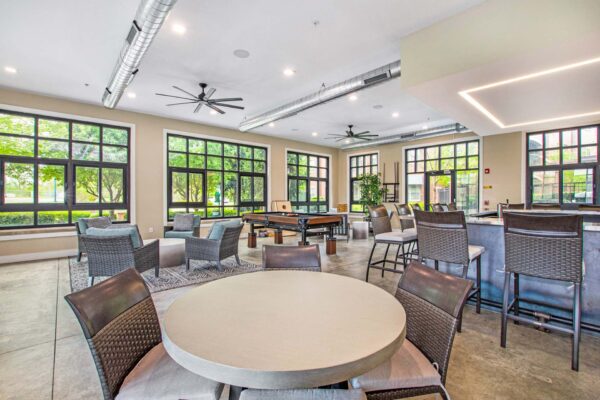 Village at Mission Farms apartments community lounge with bar, dining tables, and pool table.