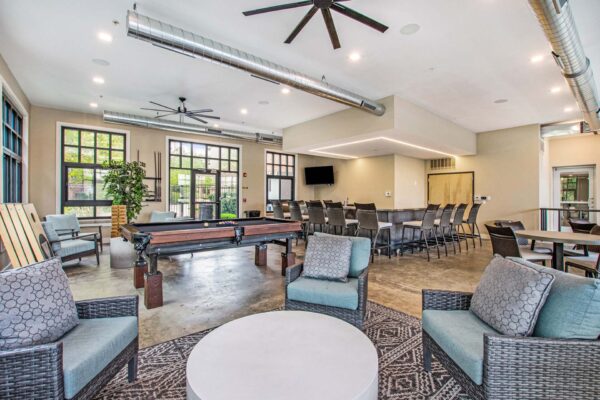 Village at Mission Farms apartments community lounge with bar, plush seating, TV, and pool table.