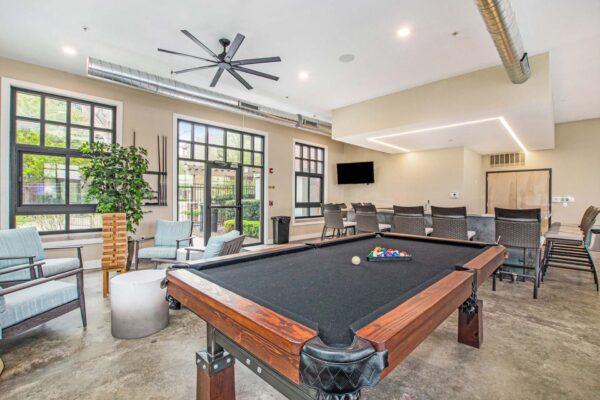 Village at Mission Farms apartments community lounge with bar, TV, pool table, and lounge chairs.