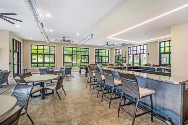 Village at Mission Farms apartment community lounge with bar and dining tables.