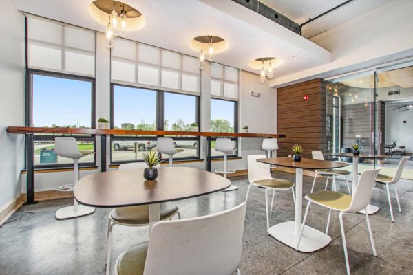 Village at Mission Farms apartment community lounge with dining tables and large windows.