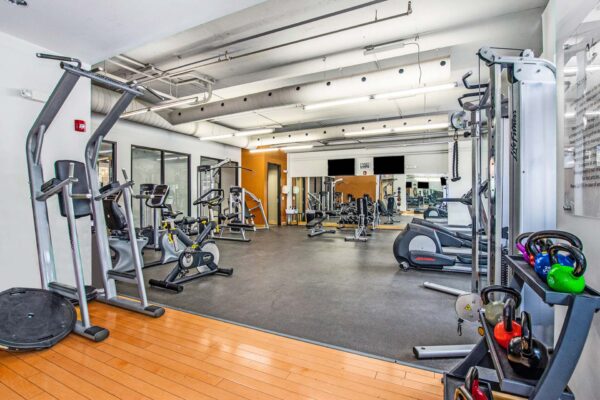 Village at Mission Farms apartments fitness center with cardio machines and weight equipment.