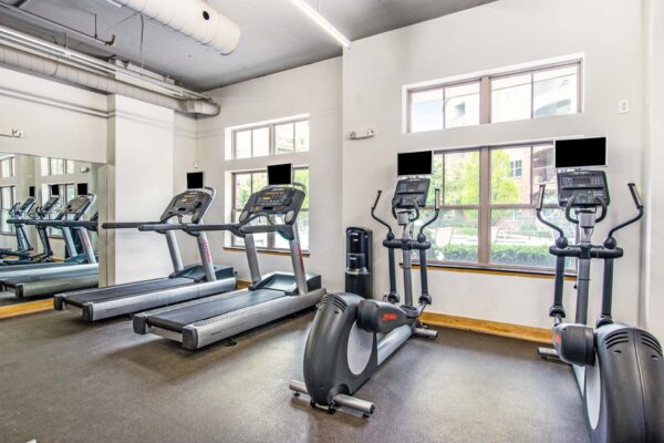 Village at Mission Farms apartments with cardio machines and large windows.