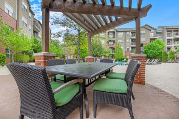 Village at Mission Farms apartments pool area with pergola and dining table.