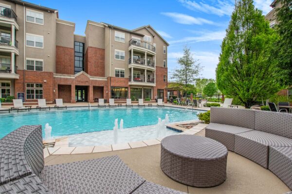Village at Mission Farms apartments pool area with fountains and round sectional outdoor couch.