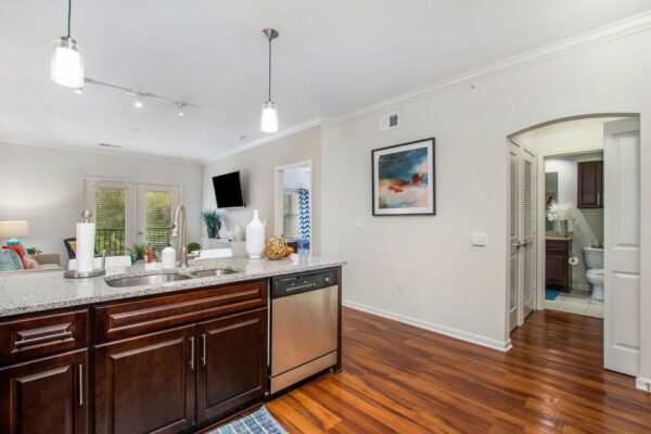 Village at Mission Farms apartment kitchen with wood style floor and cabinets, stone counters, and stainless steel appliances.