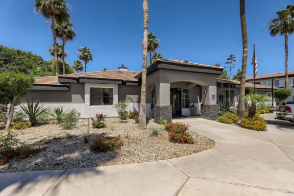 Villas at Mountain Vista Ranch apartments entrance with lush desert landscaping and tall palm trees.