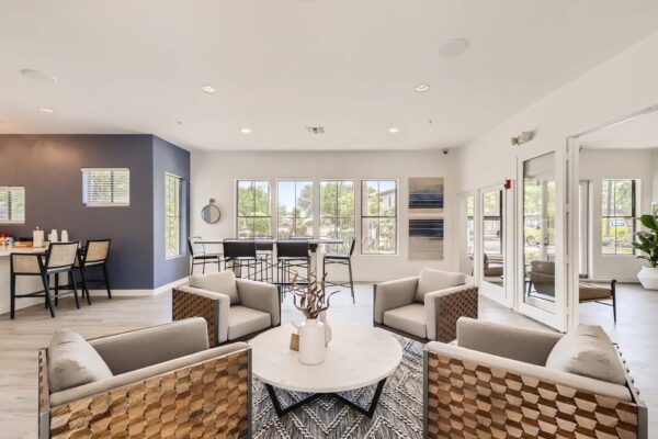 Villas at Mountain Vista Ranch apartments clubhouse with plush seating, dining table, and large windows.