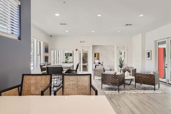 Villas at Mountain Vista Ranch apartments clubhouse with plush seating, dining table, and bright windows.