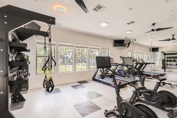 Villas at Mountain Vista Ranch apartments fitness center with cardio machines, weight equipment, and large windows.