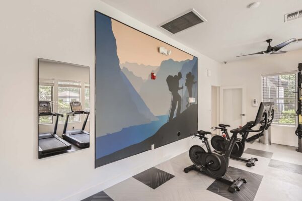 Villas at Mountain Vista Ranch apartments fitness center with cardio machines and large outdoor mural.