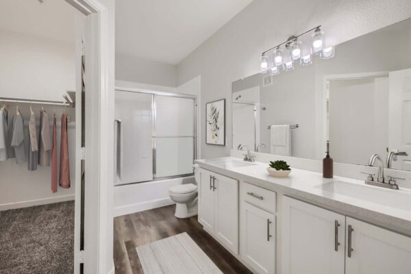 Villas at Mountain Vista Ranch apartment bathroom with wood style floor, white cabinets and counters, and tiled shower tub.